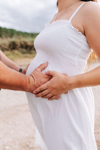Midsection of pregnant woman with man in white dress