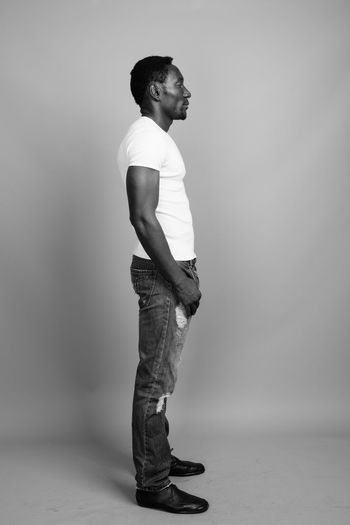 Side view of man standing against gray background