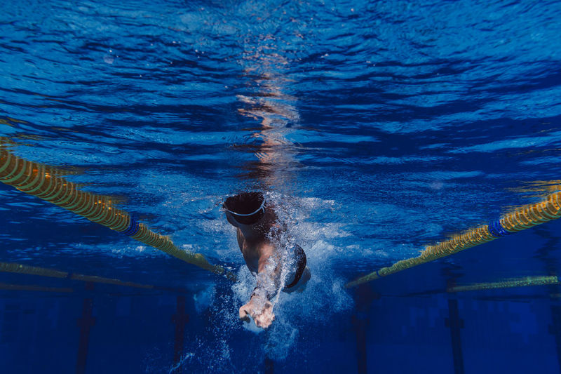 Male swimmer diving underwater in swimming pool