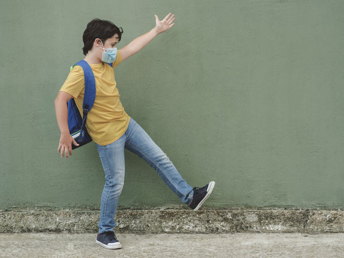 Full length of boy jumping against wall