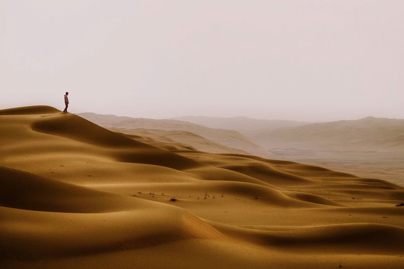 Man standing at desert against clear sky