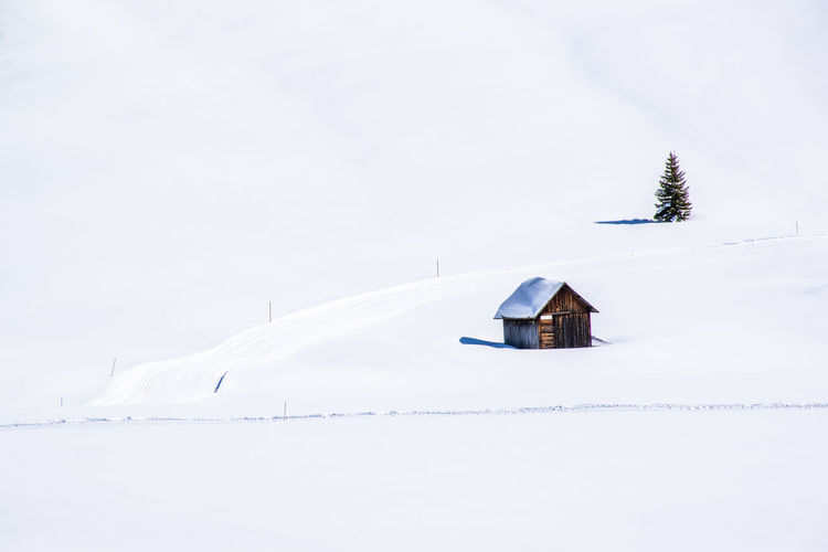 House on snow covered land against sky