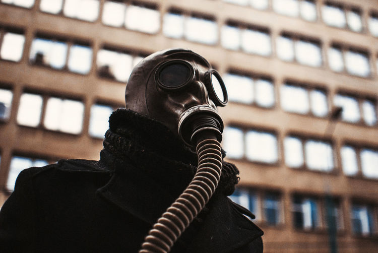 Low angle view of person wearing gas mask against building