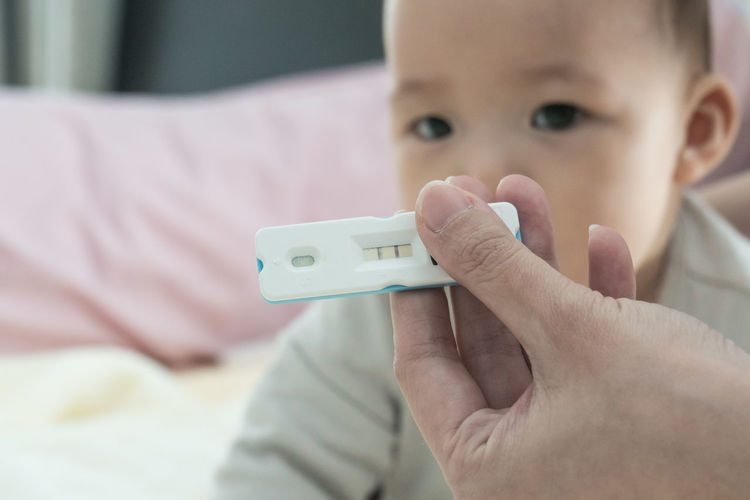 Close-up of hand holding pregnancy test against baby girl