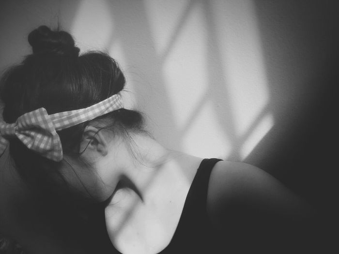Sunlight falling on woman wearing headband with tied bow by wall
