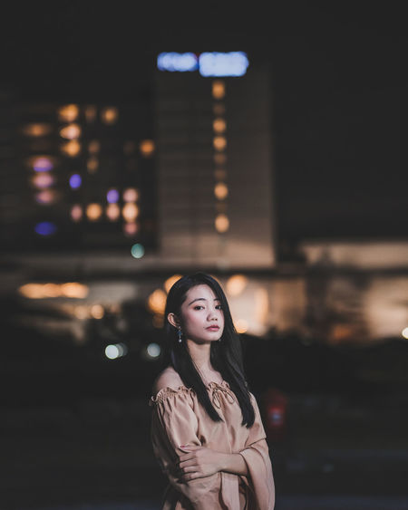 Portrait of young woman standing outdoors at night