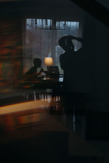 Silhouette people sitting on table in window