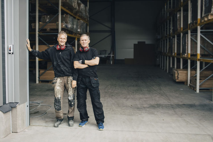 Full length portrait of confident workers standing in entrance at industry