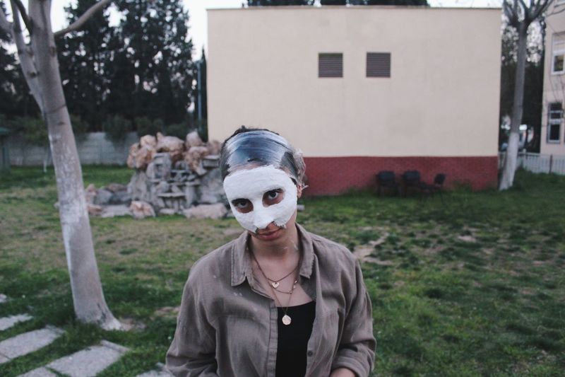 Portrait of woman with facial mask standing in back yard
