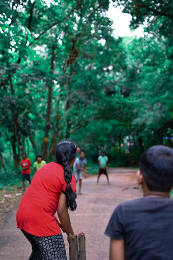Rear view of people photographing against trees