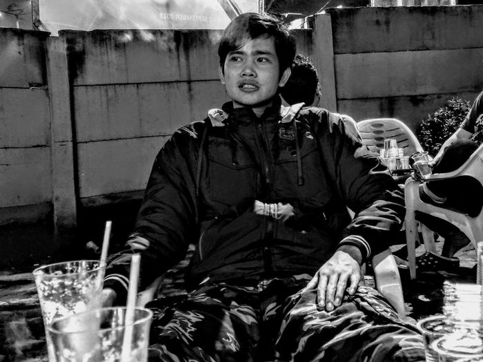 Man looking away while sitting on chair outdoors