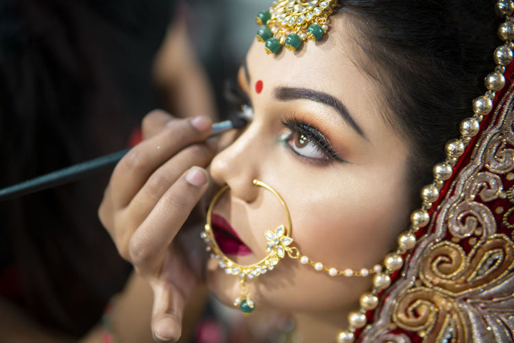 Young bride applying make-up during wedding ceremony