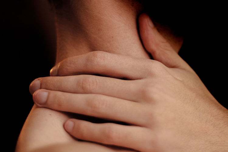 Close-up of shirtless man touching his shoulder