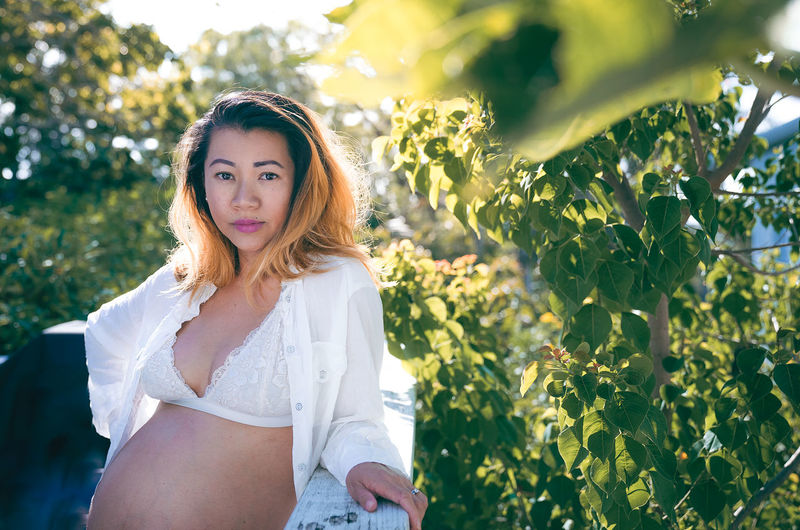 Portrait of pregnant woman standing against plants