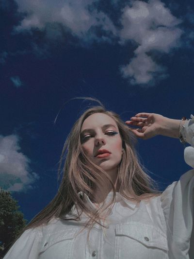 Portrait of young woman against sky