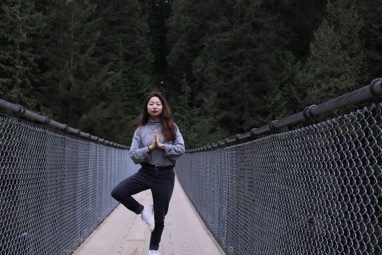 Young woman in tree pose on capilano suspension bridge against mountain