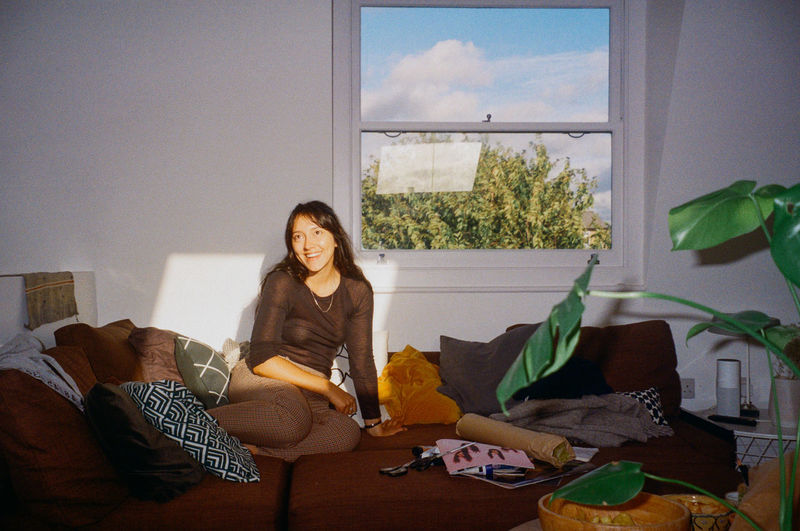 Portrait of smiling young woman sitting on sofa at home
