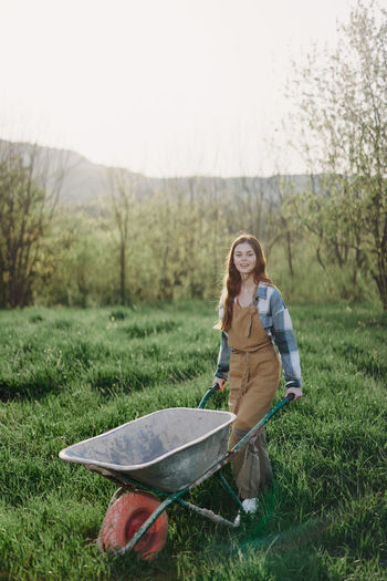 Smiling woman carrying wheelbarrow at farm