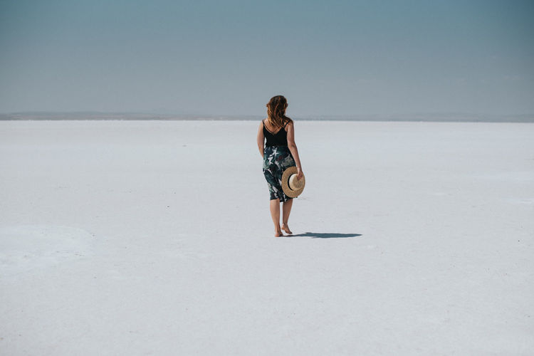 REAR VIEW OF WOMAN WALKING ON BEACH