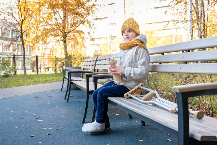 Side view of woman sitting on bench in park