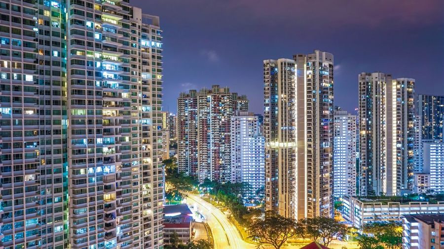 Illuminated modern buildings in city against sky at night