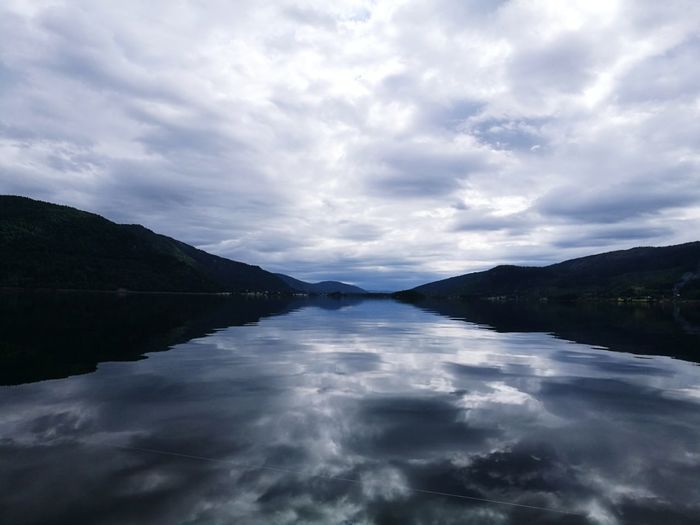 Scenic view of lake by mountains against sky