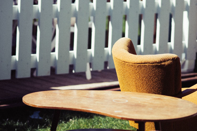 Close-up of wooden table by armchair in yard