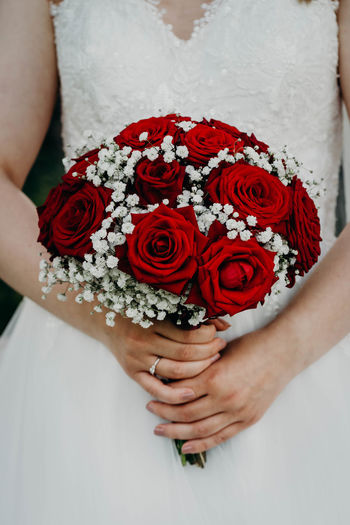 Midsection of woman holding red flower bouquet