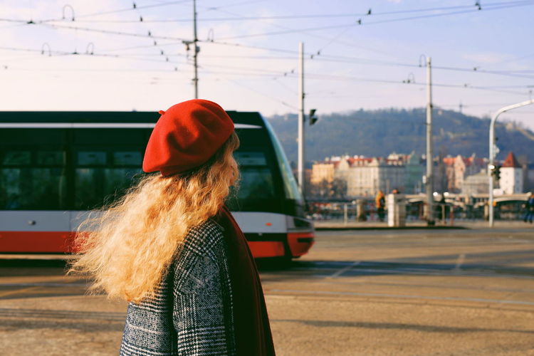 Woman wearing red hat while standing on street in city