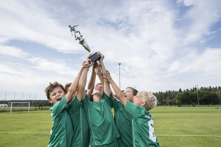 Young football players cheering with cup