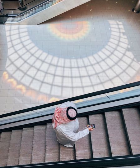 Arab man wearing the traditional clothes using the escalator 