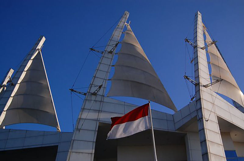 Low angle view of indonesian flag waving against building