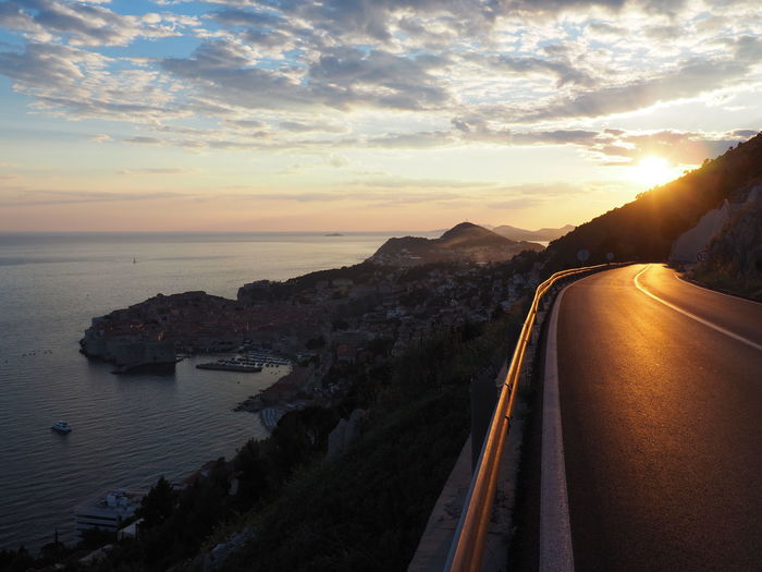 Panoramic view of road by sea against sky during sunset