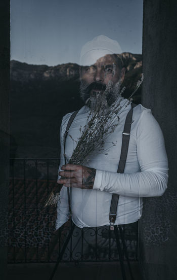 Portrait bearded man looking out window in dark room