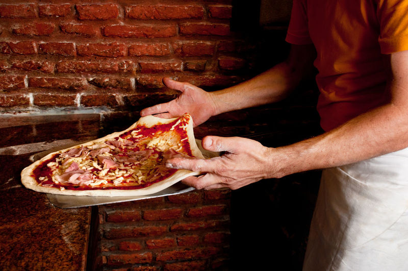 Midsection of man holding pizza