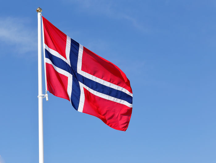 Low angle view of norweign flag against blue sky