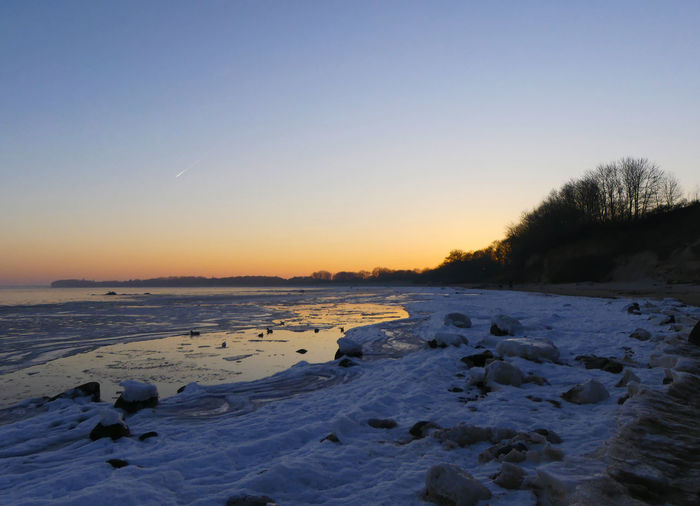 Scenic view of frozen lake against clear sky during winter