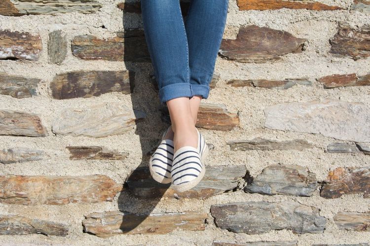 Low section of woman against stone wall