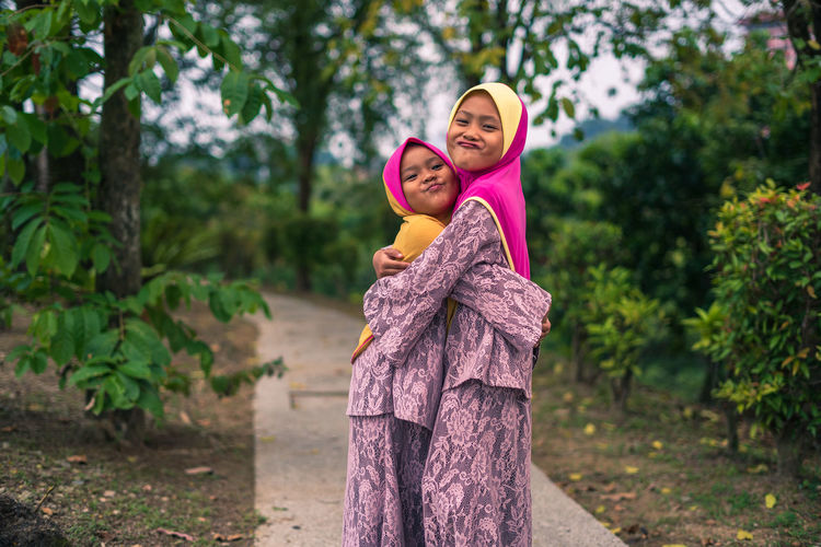 Portrait of smiling woman standing against trees