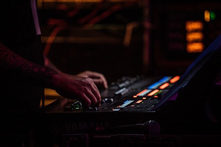Cropped hands of musician adjusting sound mixer in nightclub