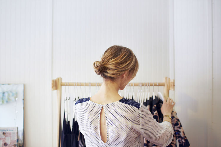 Rear view of woman arranging clothes in rack