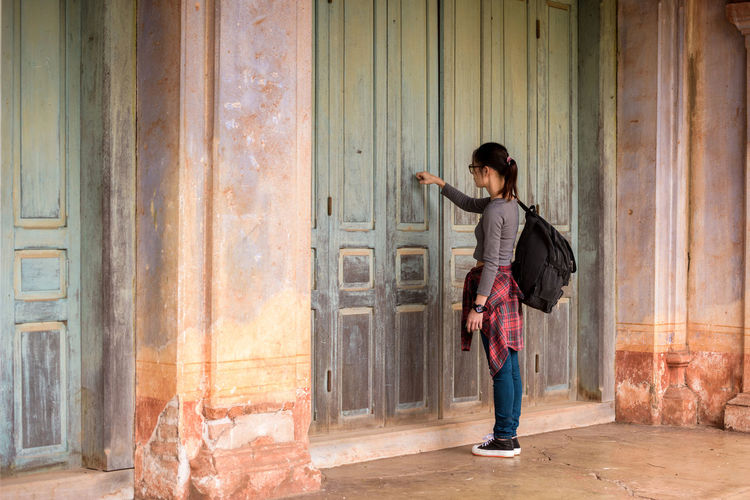 Woman knocking door of old building