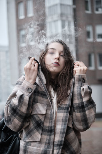 Young woman on city street exhale smoke closeup portrait
