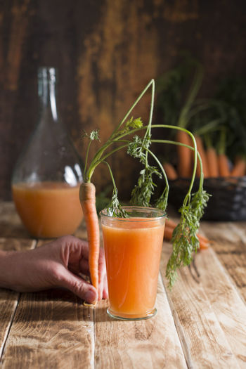 Freshly squeezed carrot juice, and raw carrots, vegetarian vegetable vitamin drink, rustic stilllife