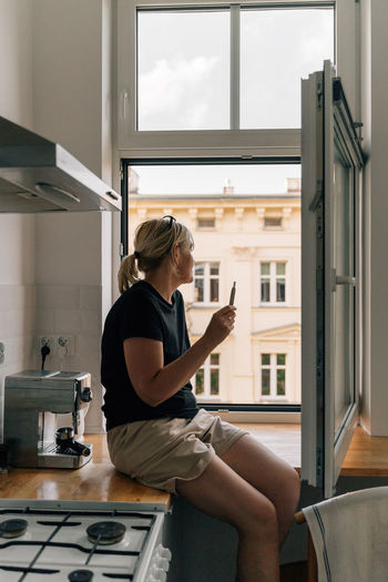 Side of woman sitting with vape at home