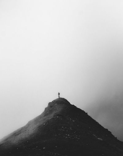 Person standing on mountain against sky during winter