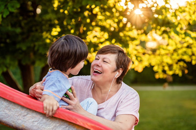 Portrait of happy smiling senior plus size woman having fun with grandson in park outdoors 