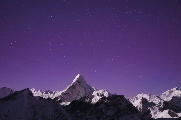 Scenic view of snowcapped mountains against star field