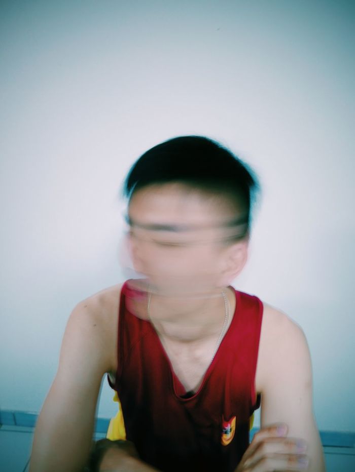 Blurred motion of young man against wall at home