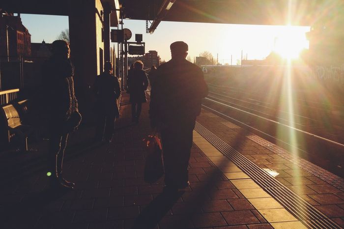 Silhouette people waiting on railway station platform